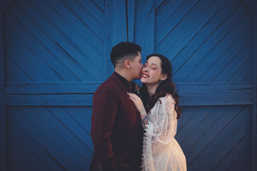 Couple sharing a tender moment in front of a rustic blue wooden door backdrop.