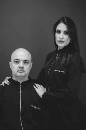 Healthcare professionals in black uniforms pose for professional portrait against gray background.