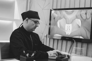 Healthcare provider reviews dental scan on monitor while working at desk.