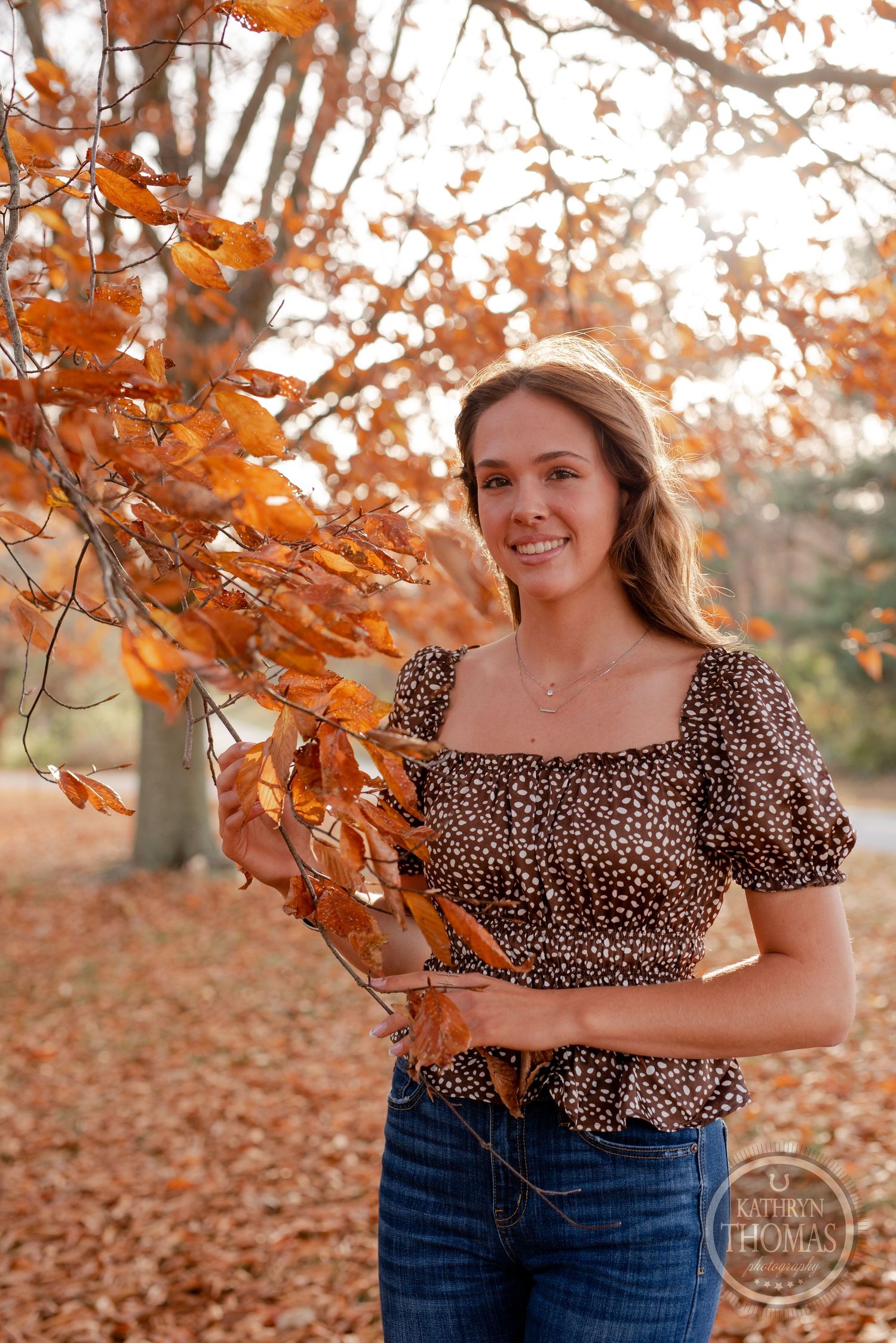 Autumn outdoor portrait next to orange leaves wearing puff sleeve animal print top.