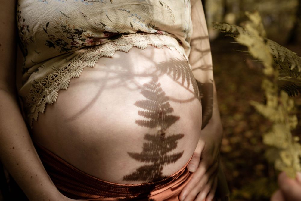 Artistieke schaduw op zwangere buik in warme kleuren – zwangerschapsfotografie Gelderland