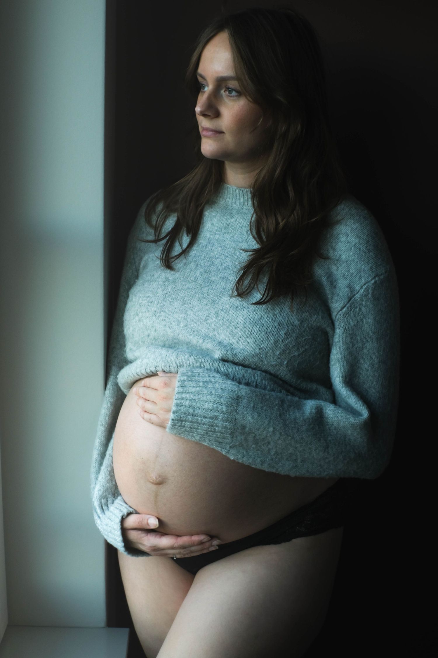 Portret van zwangere vrouw in zacht daglicht bij raam