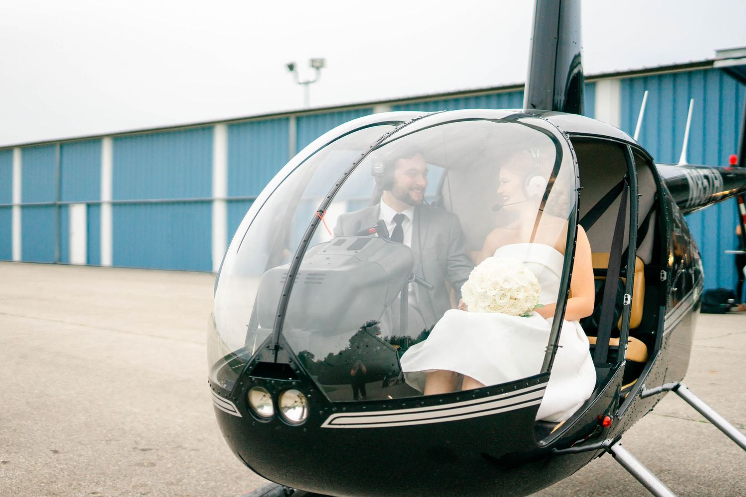 A person sitting in a helicopter with a clear dome canopy. Katie Gibbons Photography