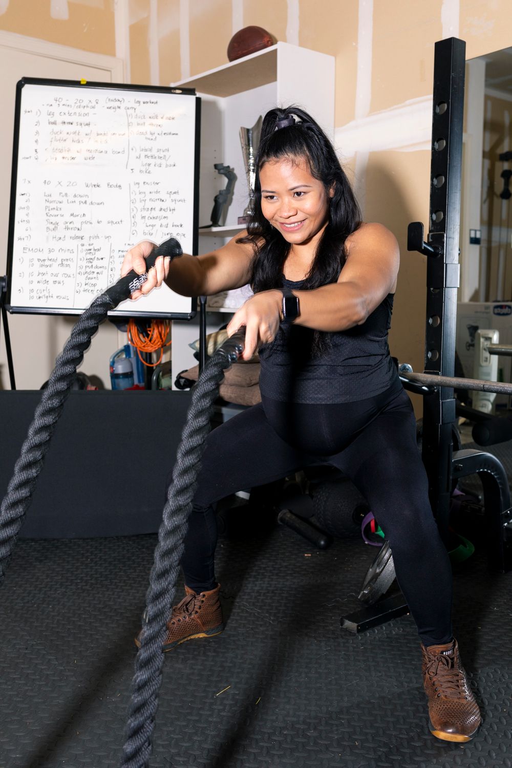 A soon-to-be mother using battling ropes and smiling.