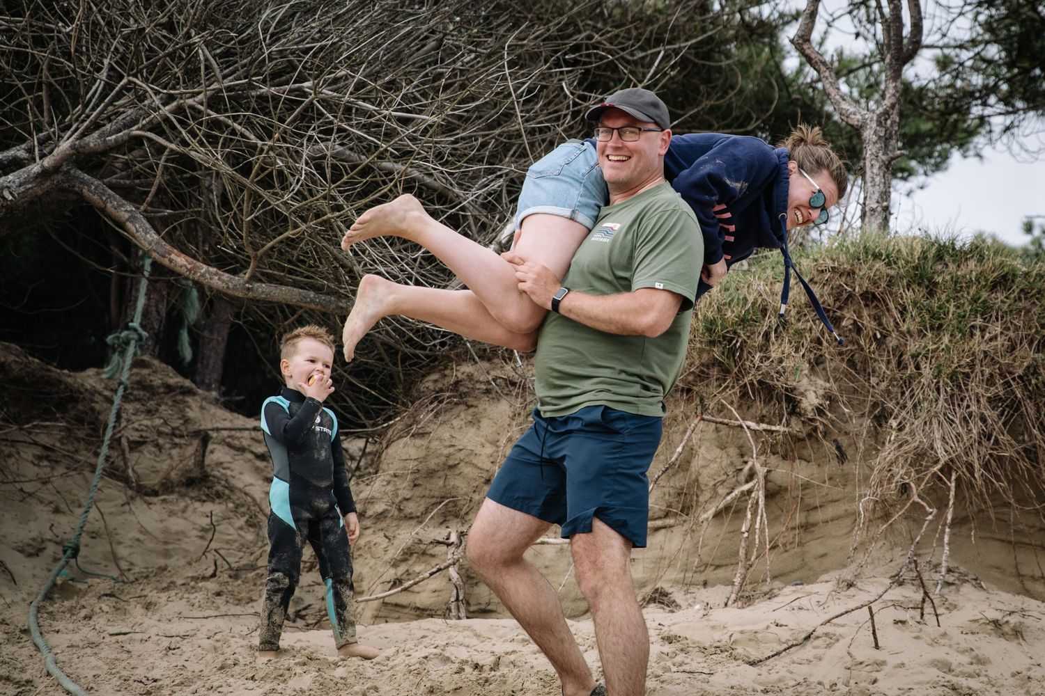 Family having fun and playing together on sandy hillside during outdoor adventure.