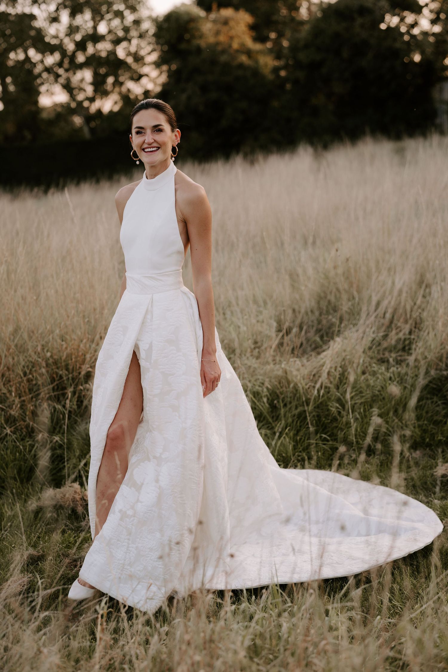bride stood in long grass at marquee wedding in islip in oxfordshire