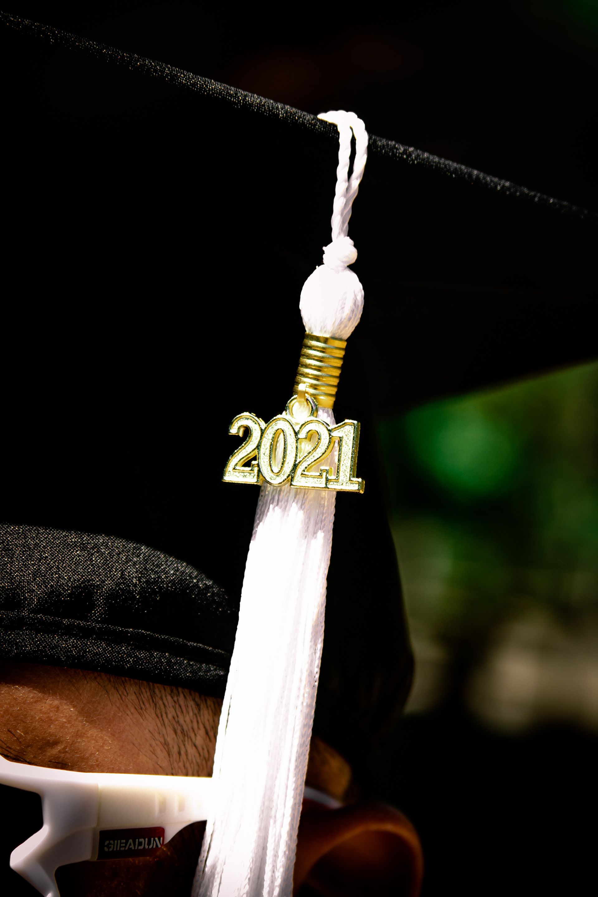 Graduation tassel and 2021 charm silhouetted against dark background.