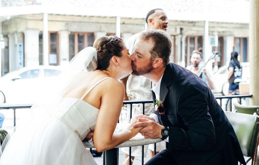 A couple kiss across a table at Cafe du Monde in the French Quarter New Orleans.