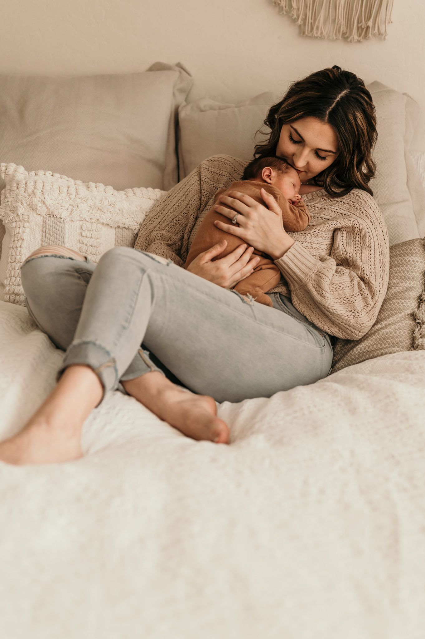 Cozy moment of parent cradling sleeping newborn on white bedding.