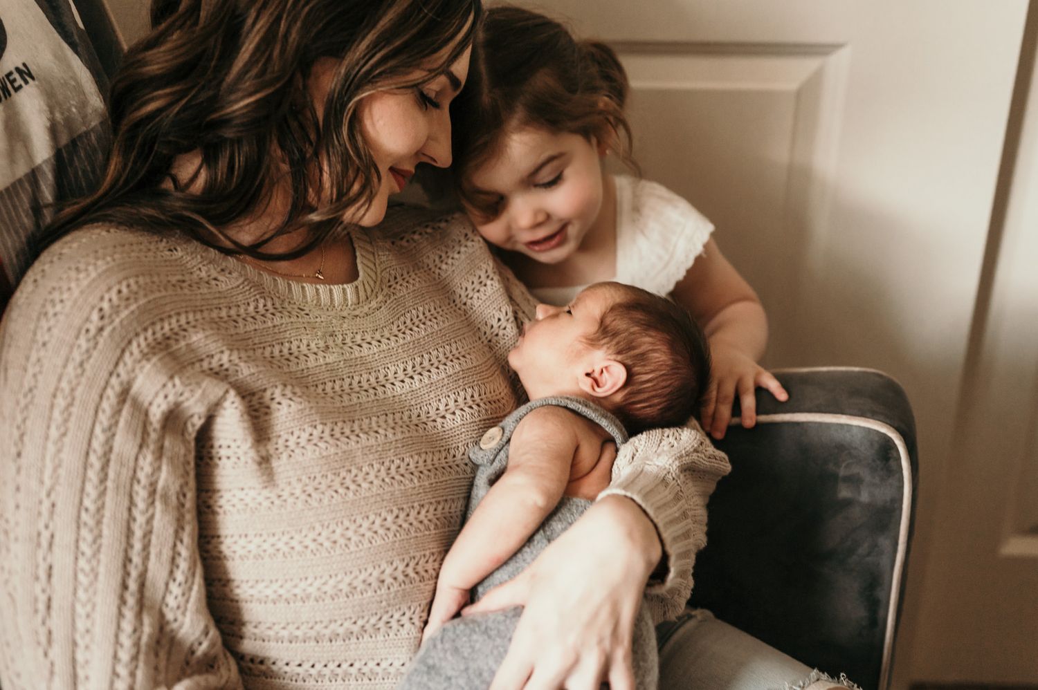 Tender family moment as parent and children cuddle together on chair.