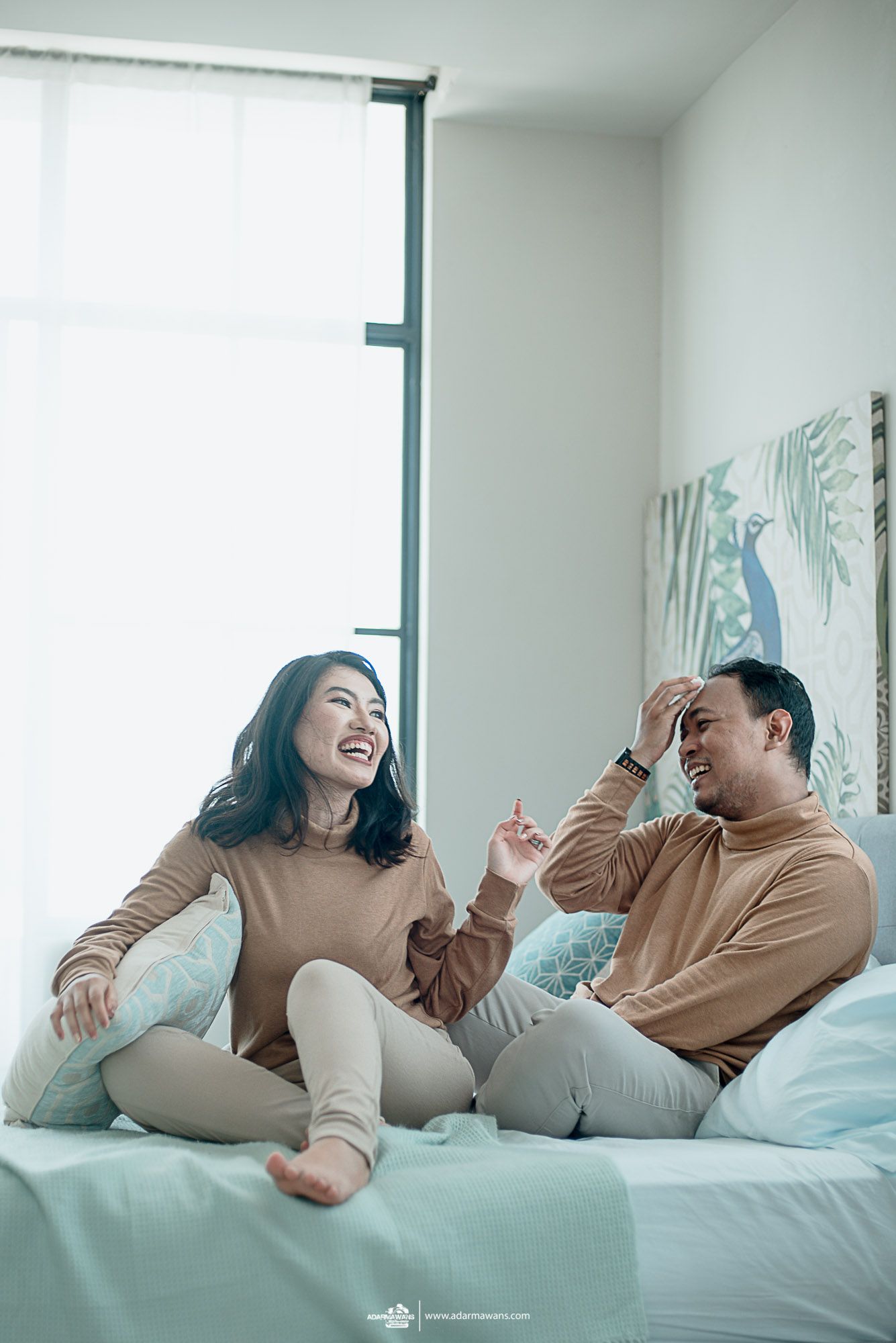 A couple laughs together while relaxing on a light blue couch.