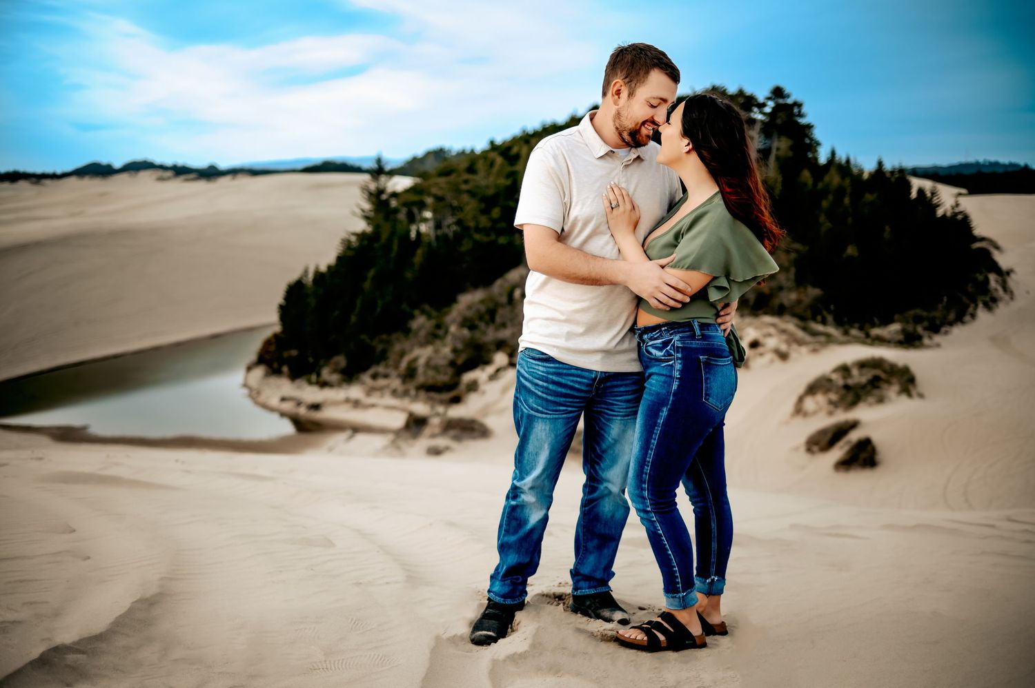 Romantic couple posing together on sandy dunes during a beach photoshoot.