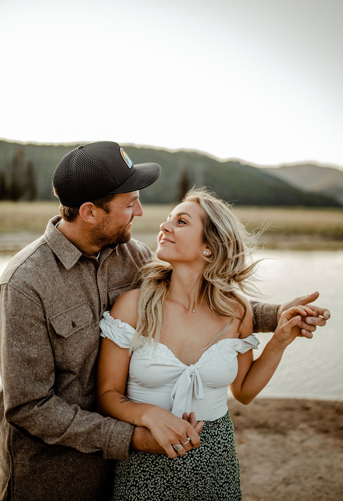 Dancing couple shares romantic moment by mountain lake at sunset.