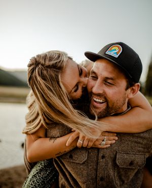 A joyful couple shares an intimate moment outdoors with natural lighting and mountains in background.