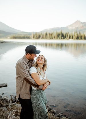Tender embrace by pristine mountain lake with evergreen forest backdrop.