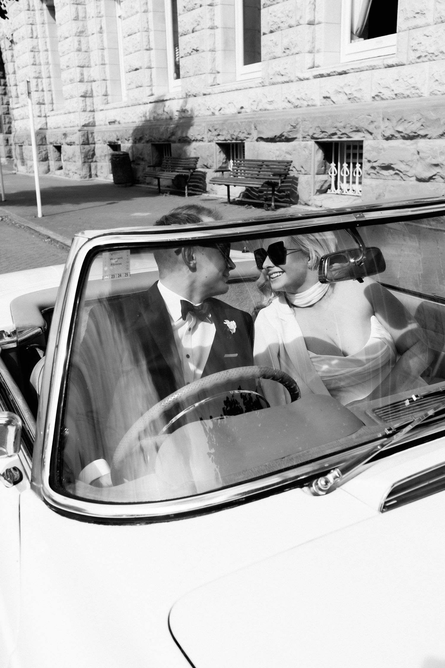 Black and white photo of newlyweds sitting in vintage convertible Mercedes-Benz.
