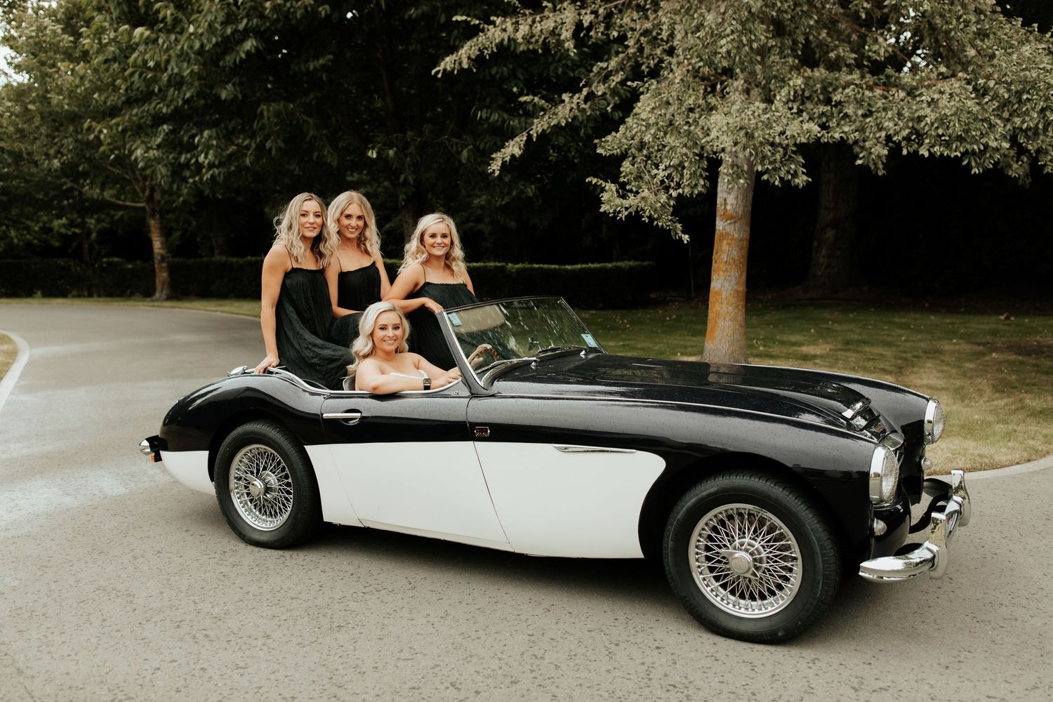Classic black and white Austin Healey sports car with wedding party.