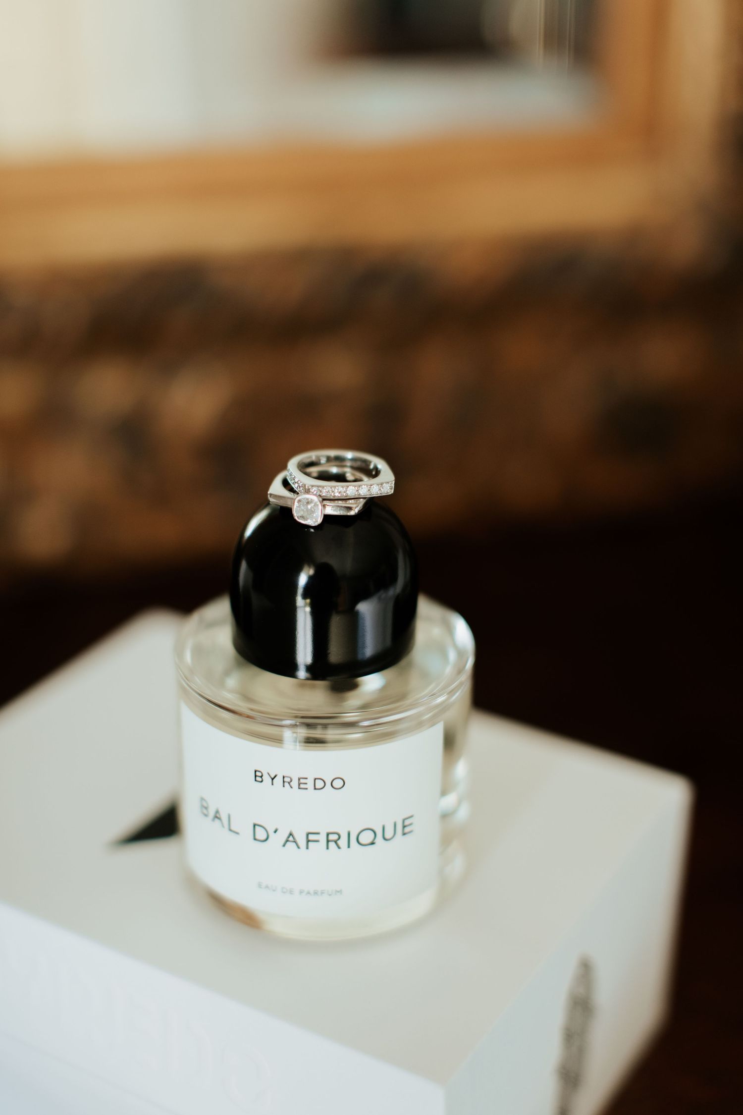 Wedding rings placed on Byredo Bal D'Afrique perfume bottle.