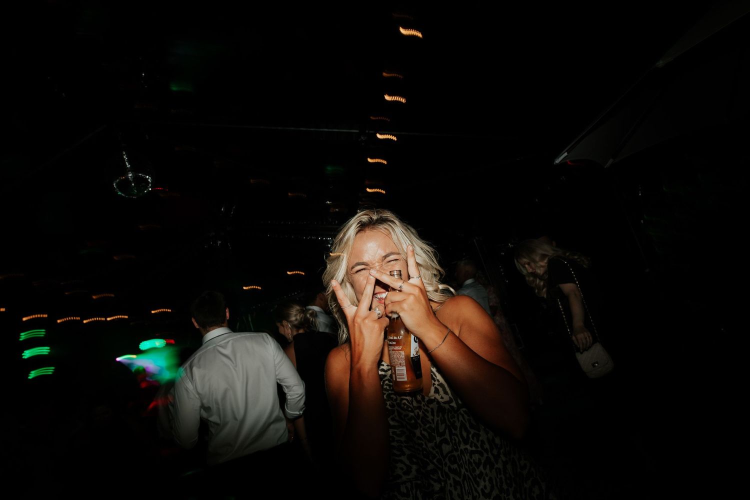 A dimly lit nightclub scene with dancing and colorful lighting effects.