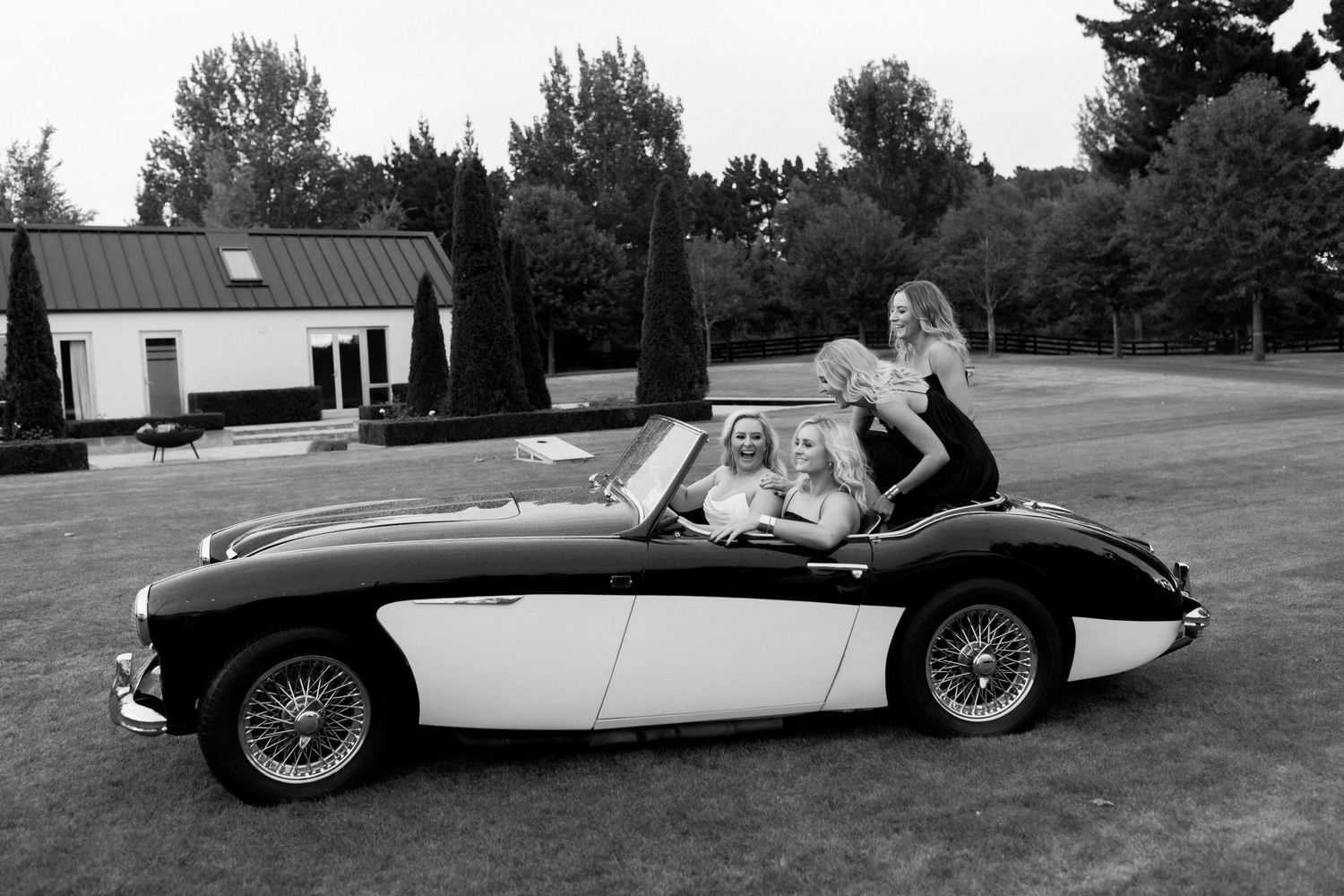 Black and white photo of classic Austin Healey sports car with passengers.