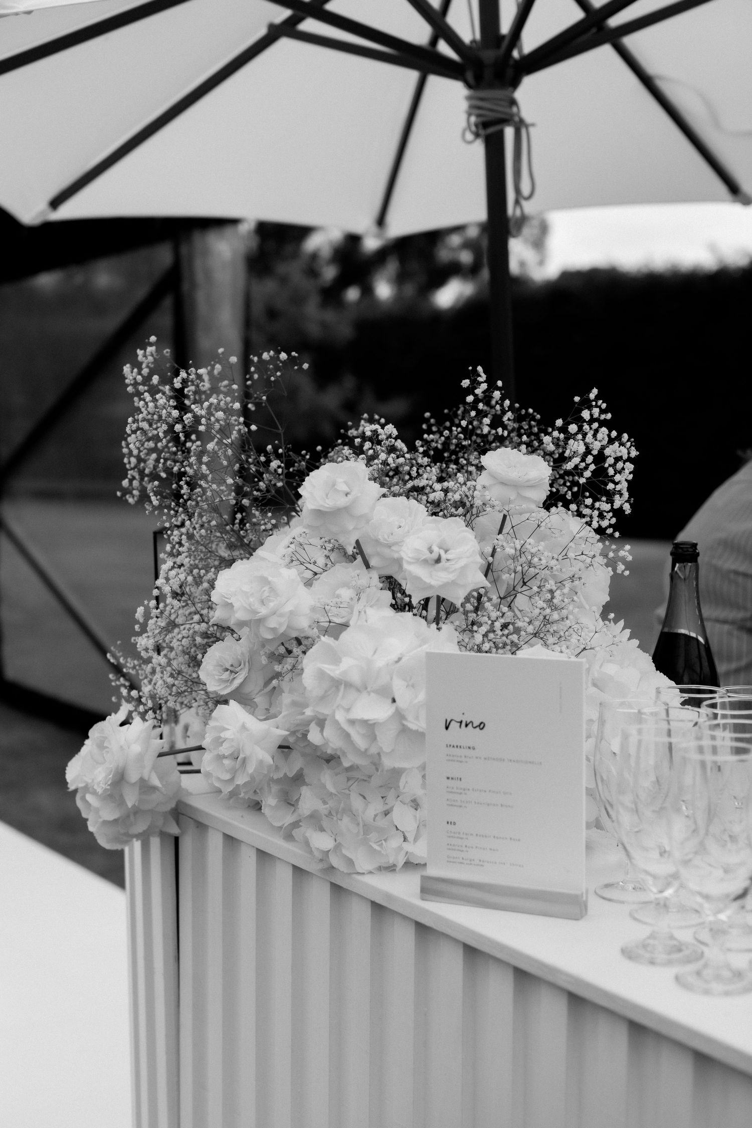 Romantic floral arrangement with white roses and baby's breath under a patio umbrella.