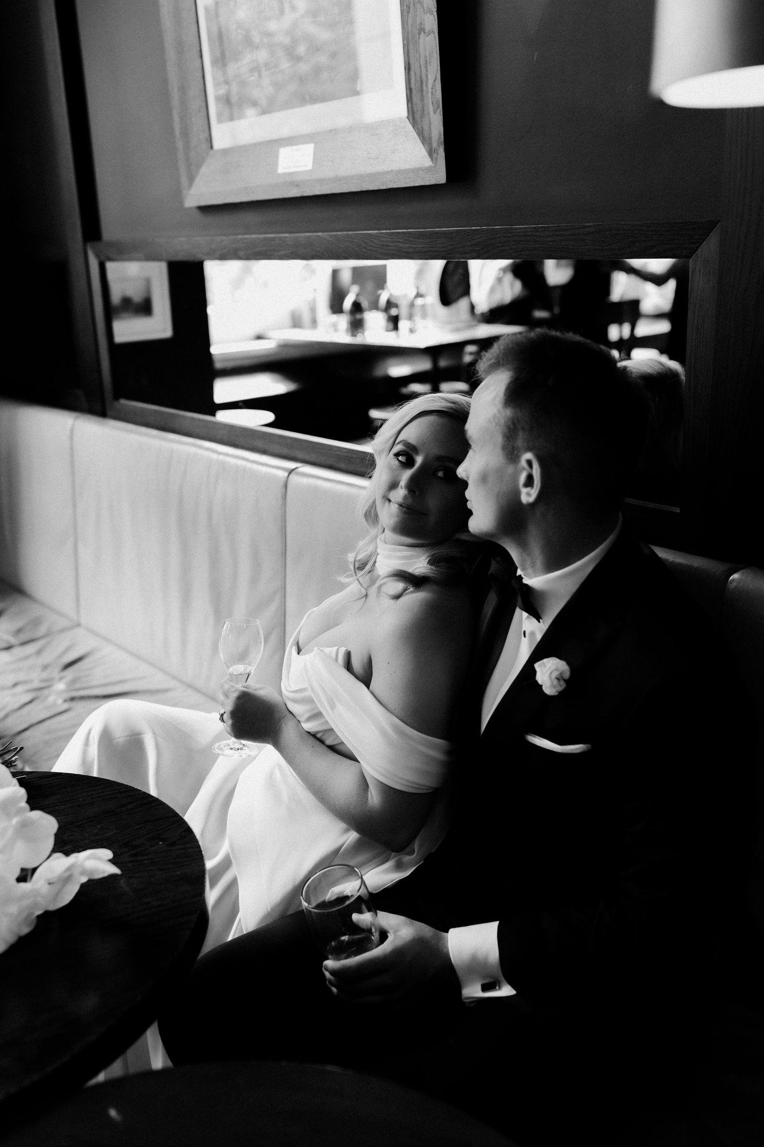 Black and white intimate portrait of newlyweds relaxing in a cozy lounge setting.