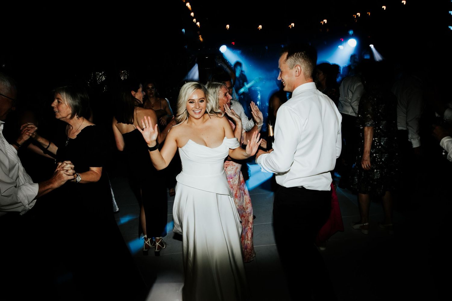 People dancing at a reception with blue stage lights in the background.
