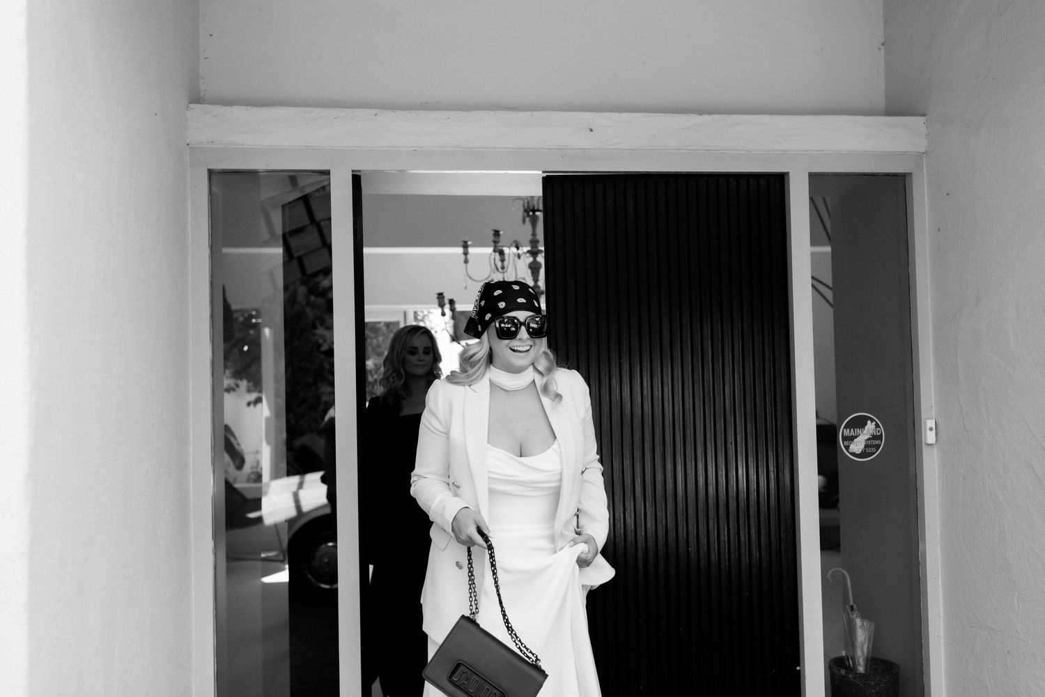Black and white photo of a fashionable ensemble with white outfit and designer handbag.