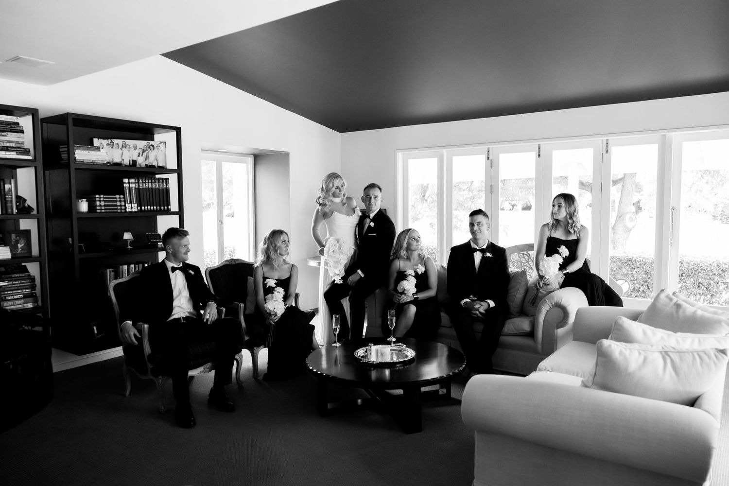 Wedding party lounges together in modern room with black and white decor.