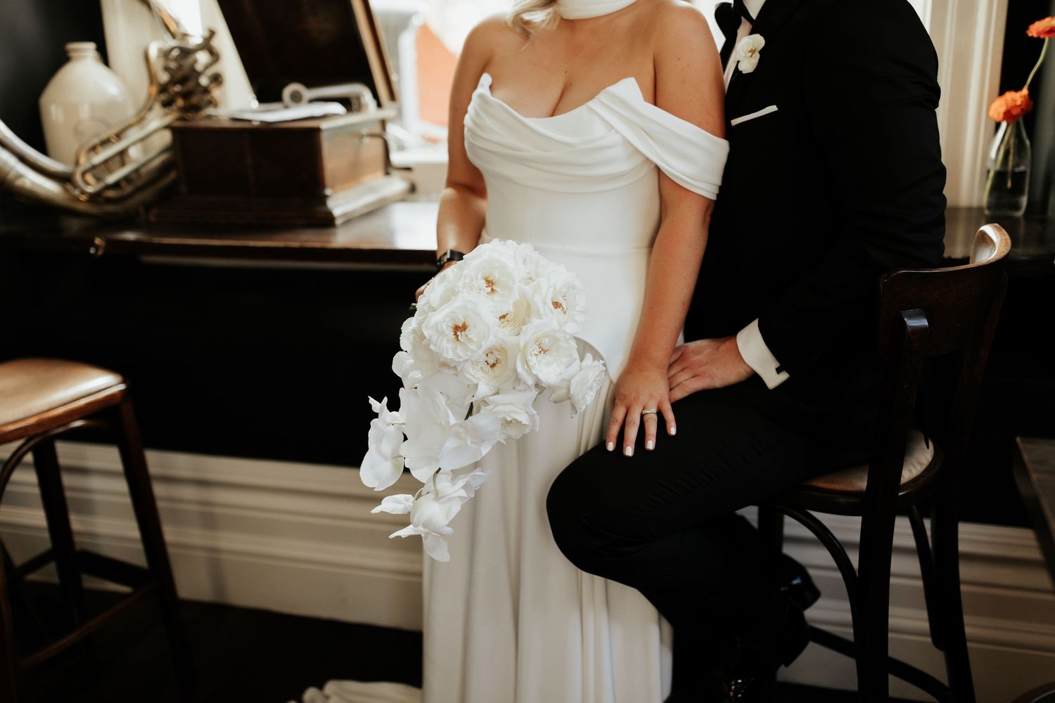 Elegant wedding couple in black and white formal attire with a cascading white orchid bouquet.