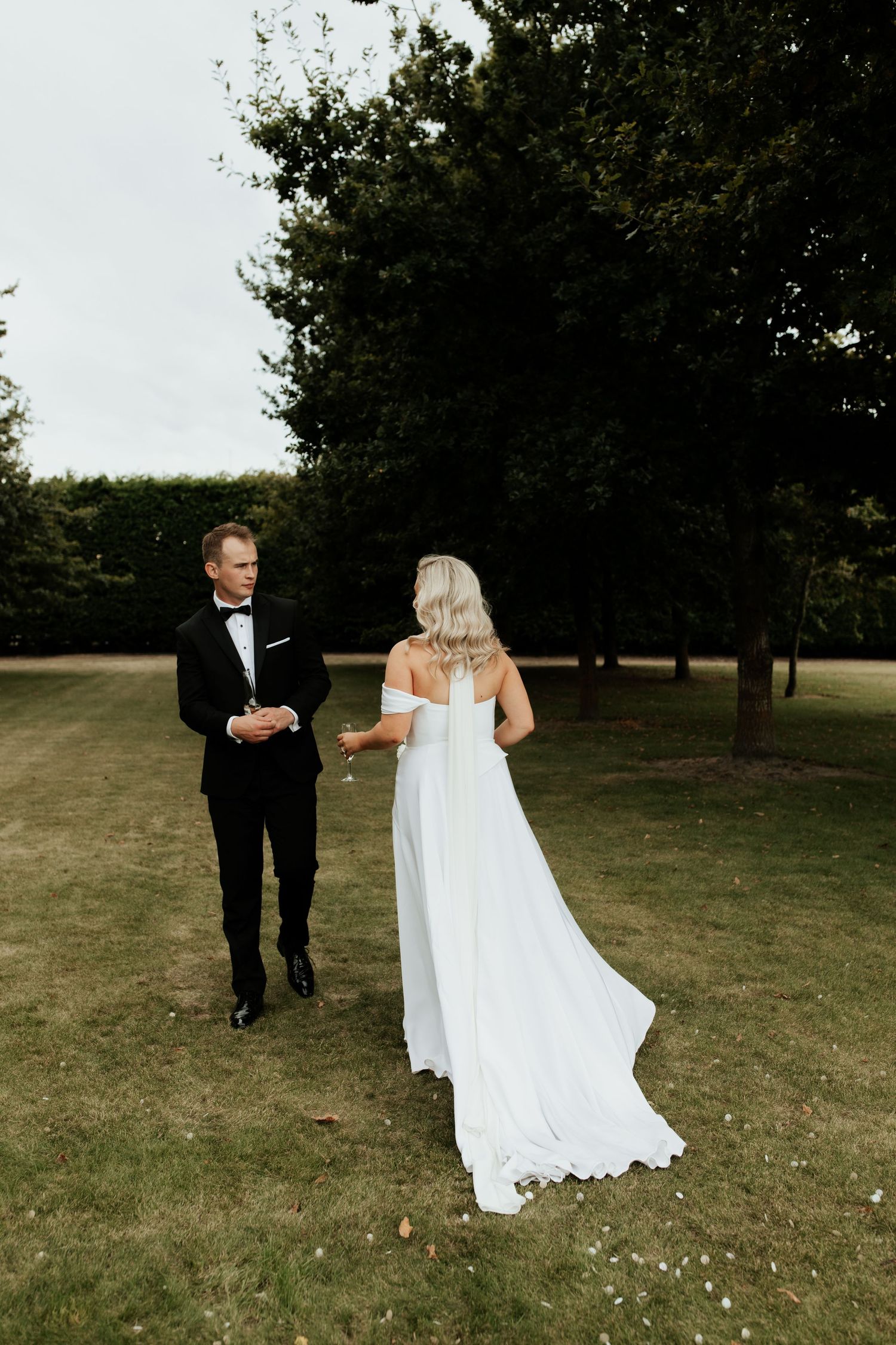 Elegant couple walking through garden setting during wedding photoshoot.