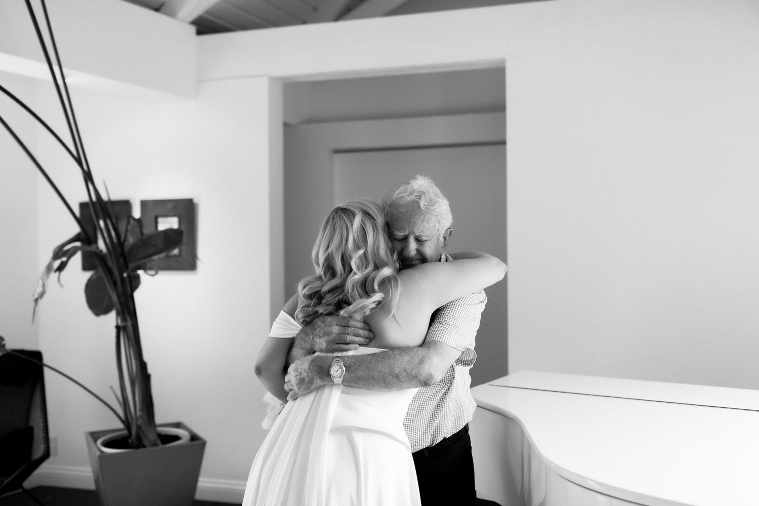 Black and white photo capturing tender moment of dress preparation.