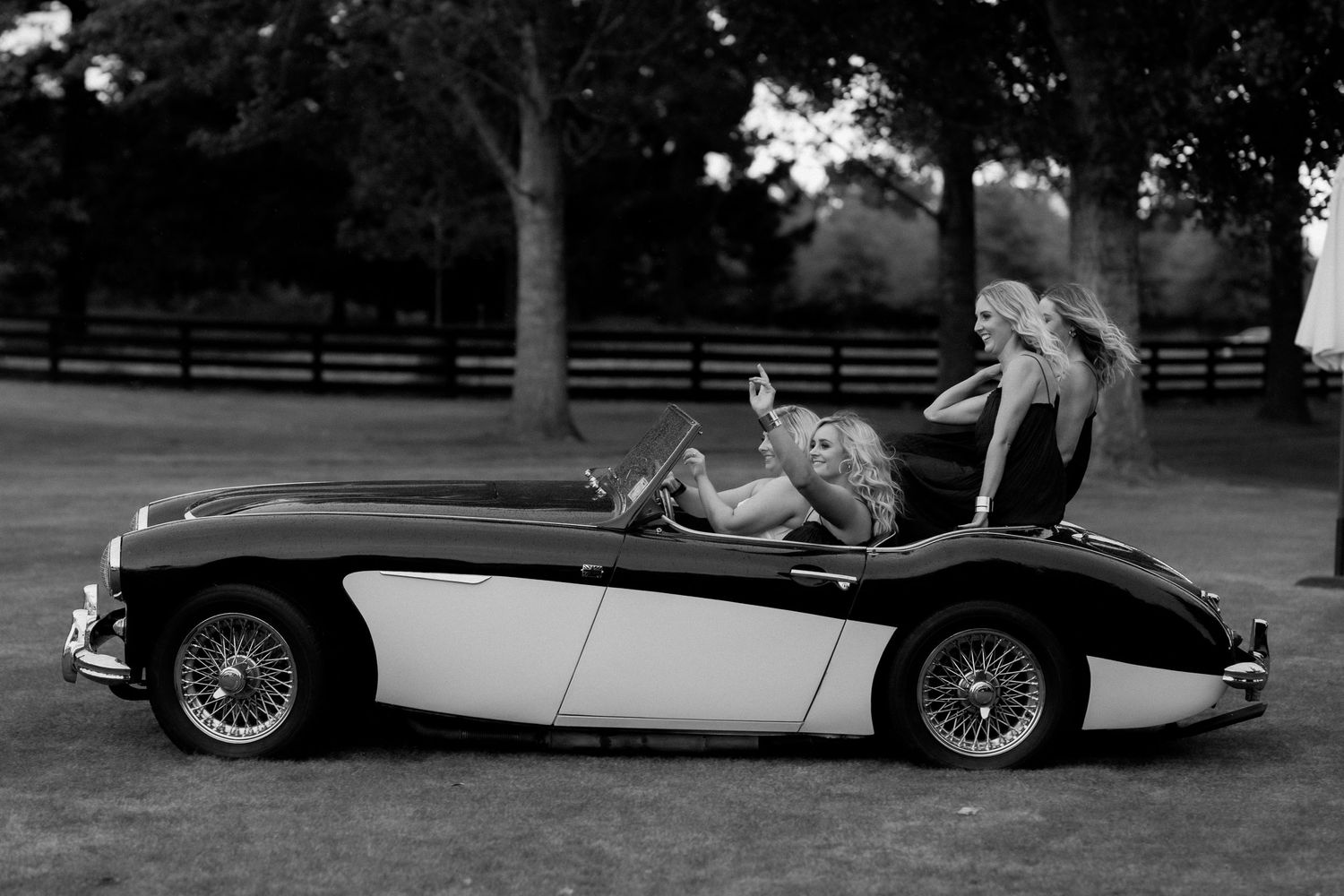 Classic vintage sports car with black and white two-tone paint in countryside setting.