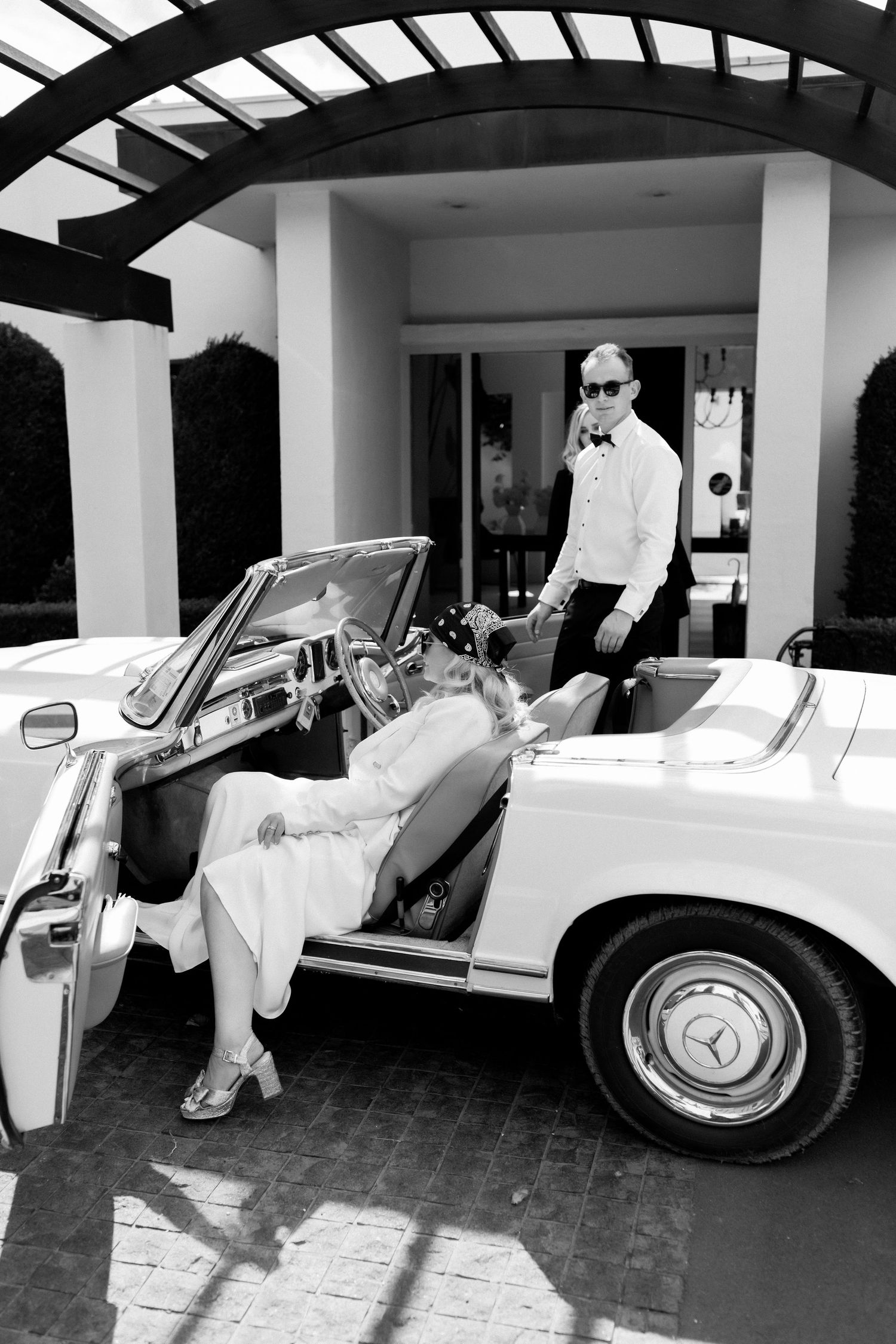 Black and white photo of classic Mercedes convertible with vintage style wedding attire.
