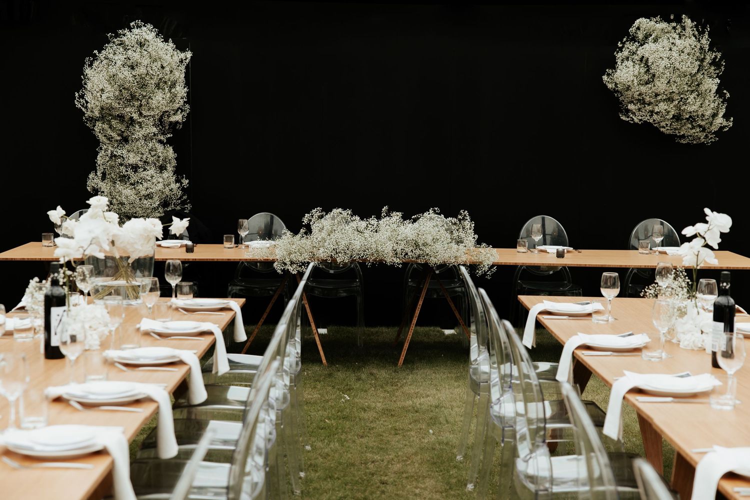 Wedding reception tables arranged with white linens and floral centerpieces under string lights.