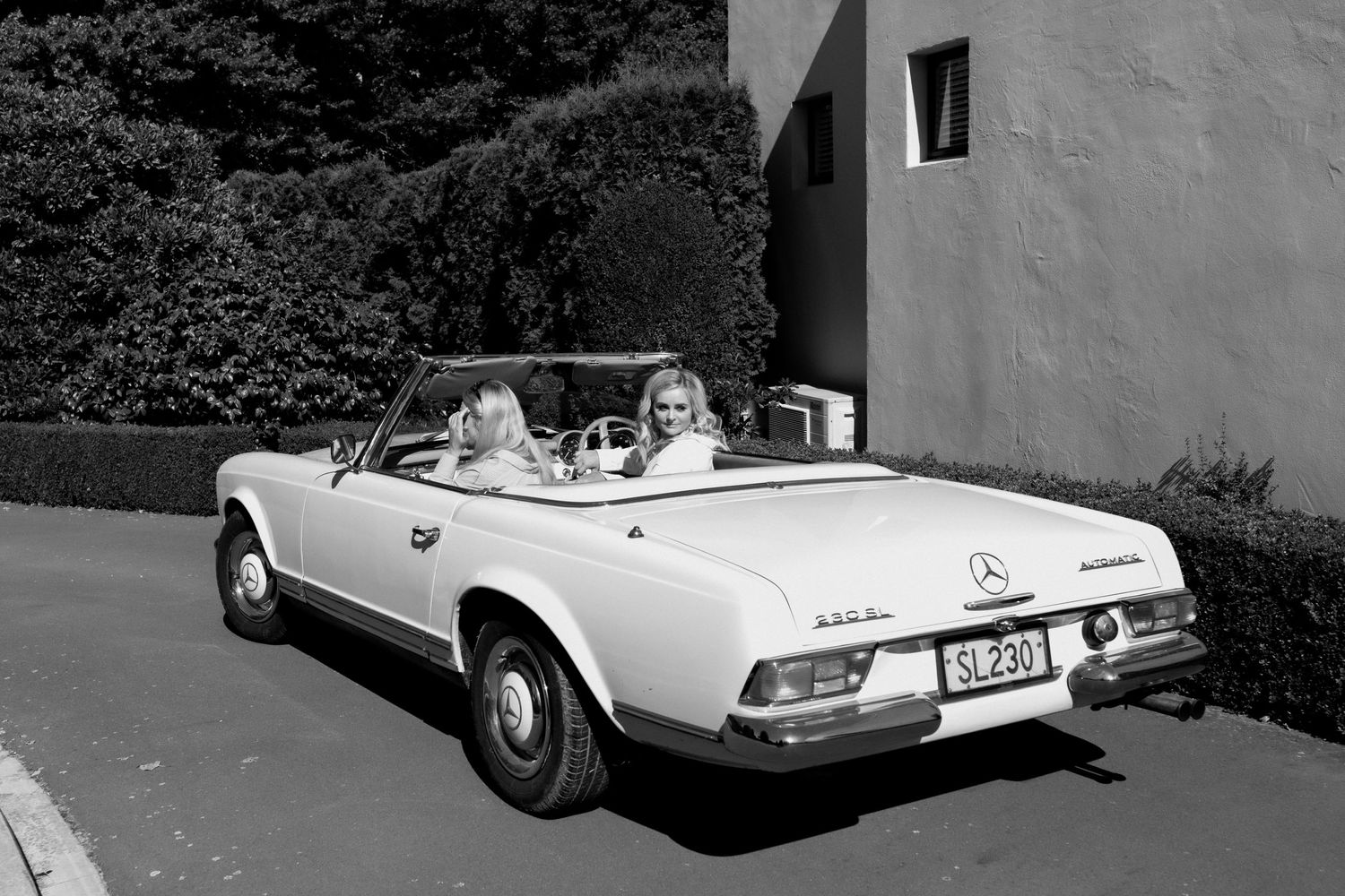 Vintage white Mercedes-Benz convertible parked outside a building in black and white.