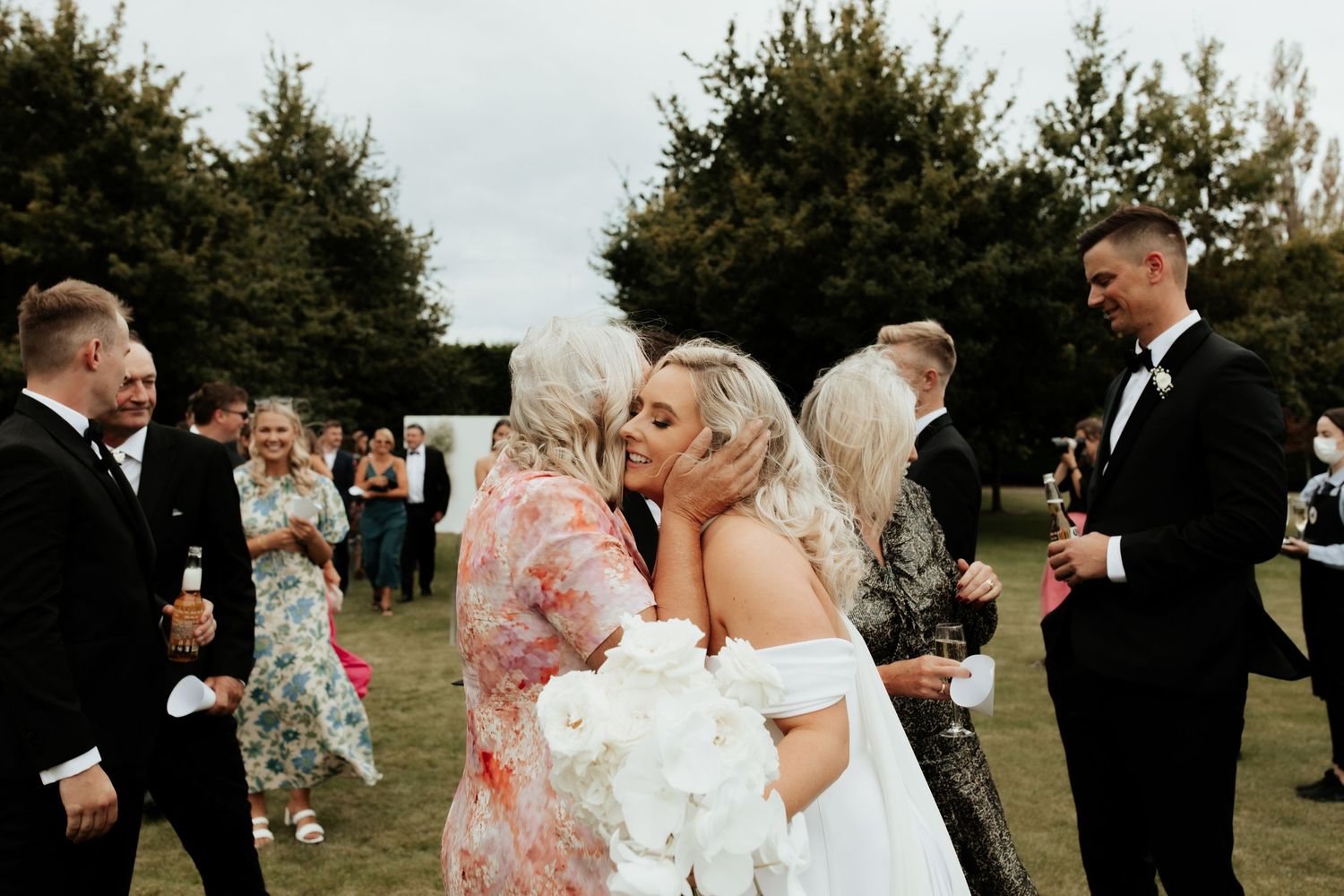 Wedding guests mingling outdoors during reception celebration.