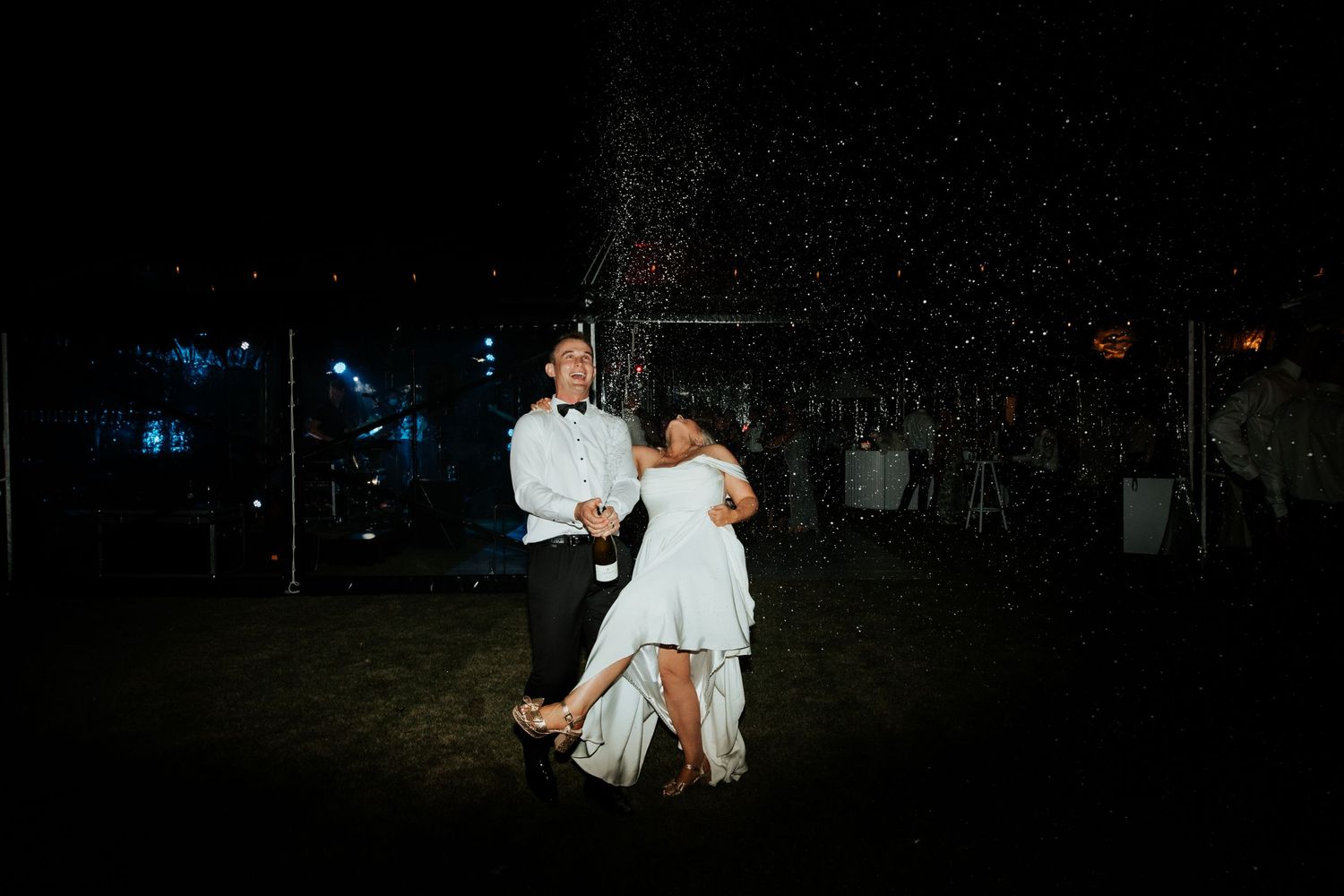 A romantic dance moment captured under twinkling lights in a dark outdoor setting.