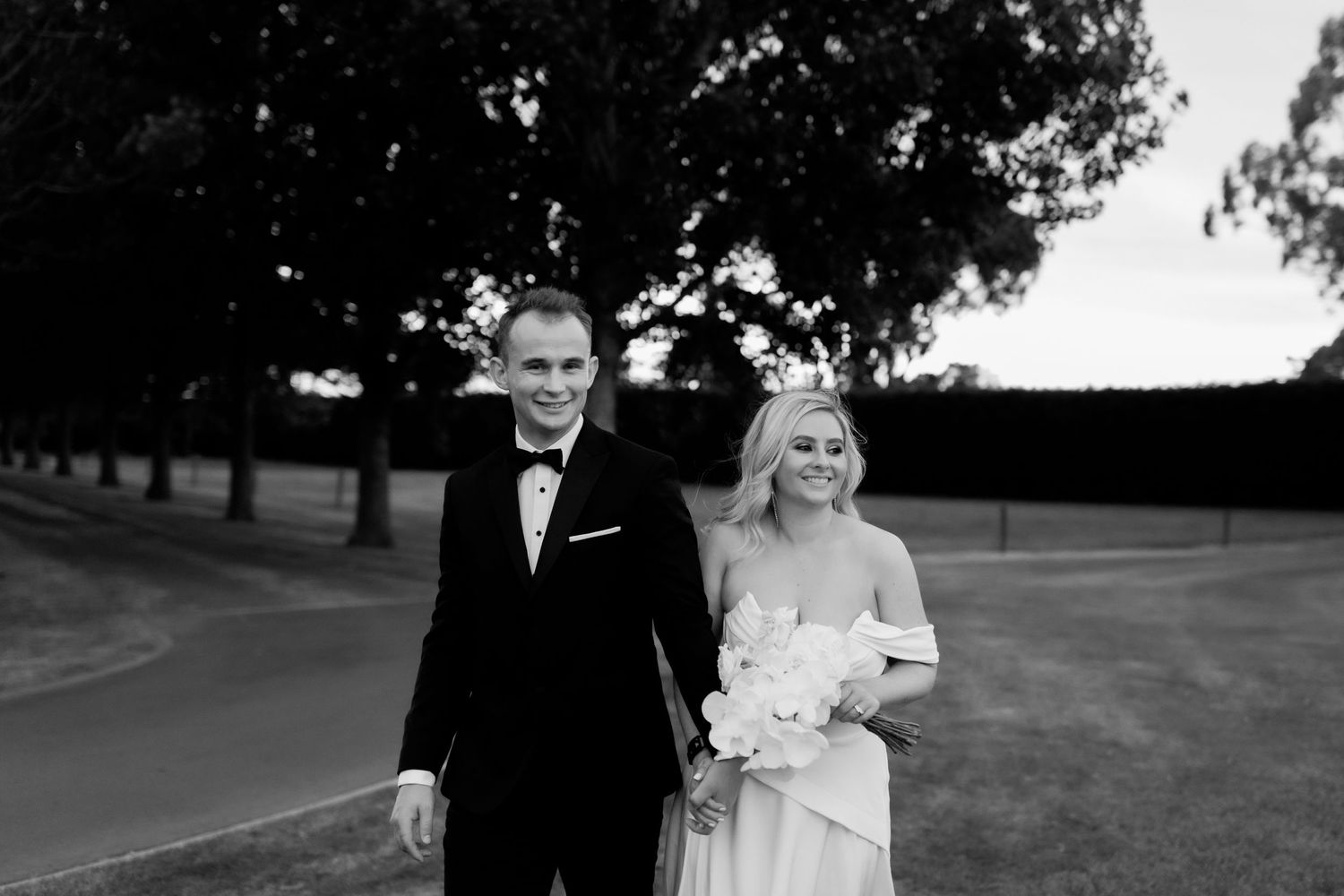 Black and white portrait of newlyweds walking together on a winding path.