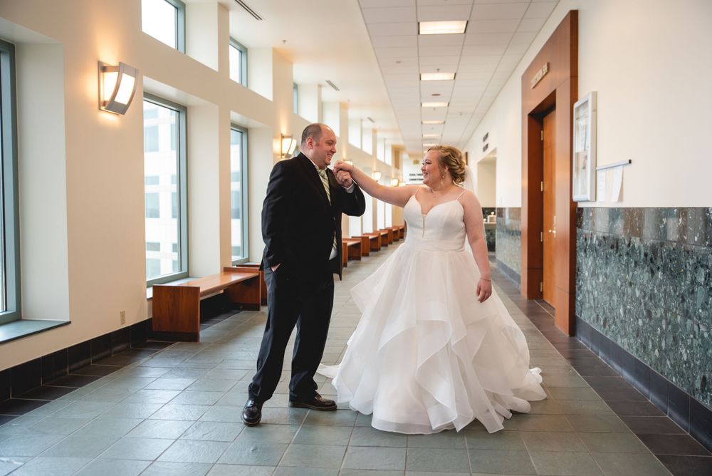 groom kissing brides hand in hallway of court hosue