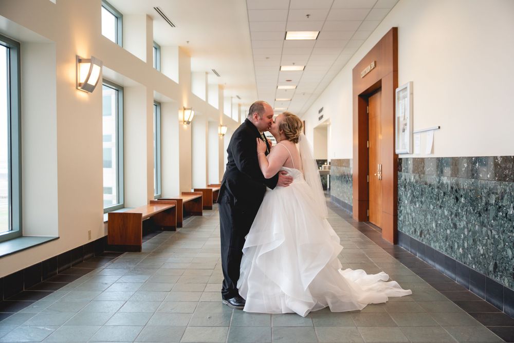 bride and groom kissing in hallway of courthouse