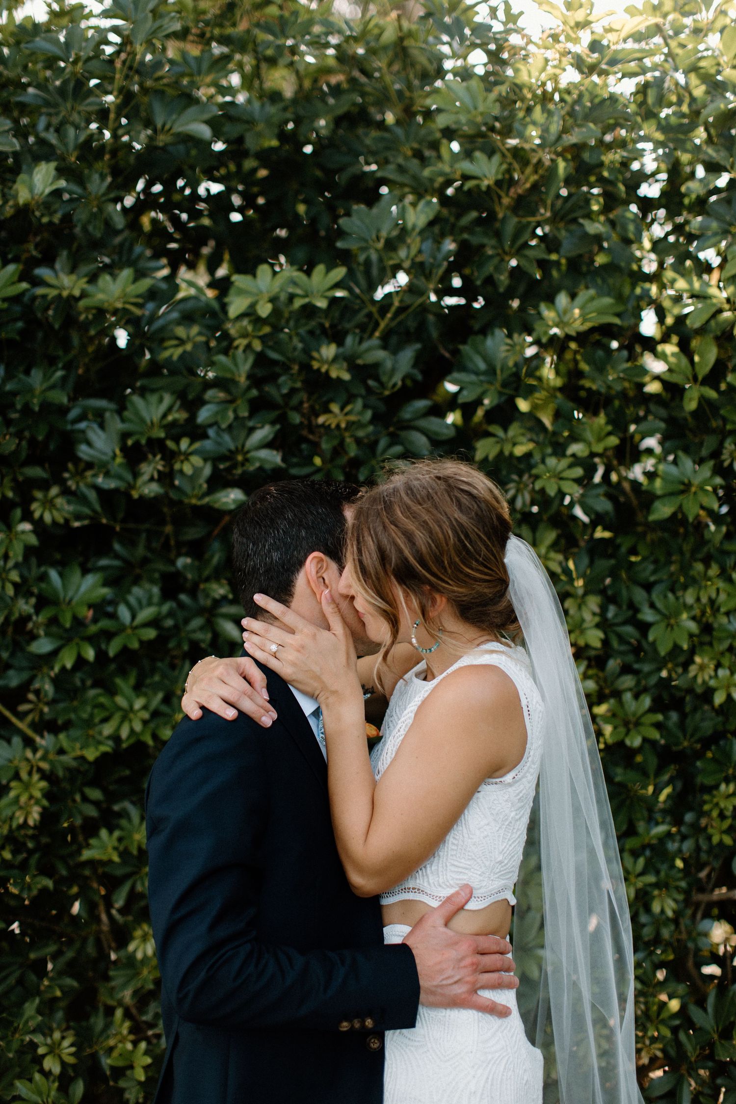 Romantic wedding moment captured through soft lens with natural garden backdrop.