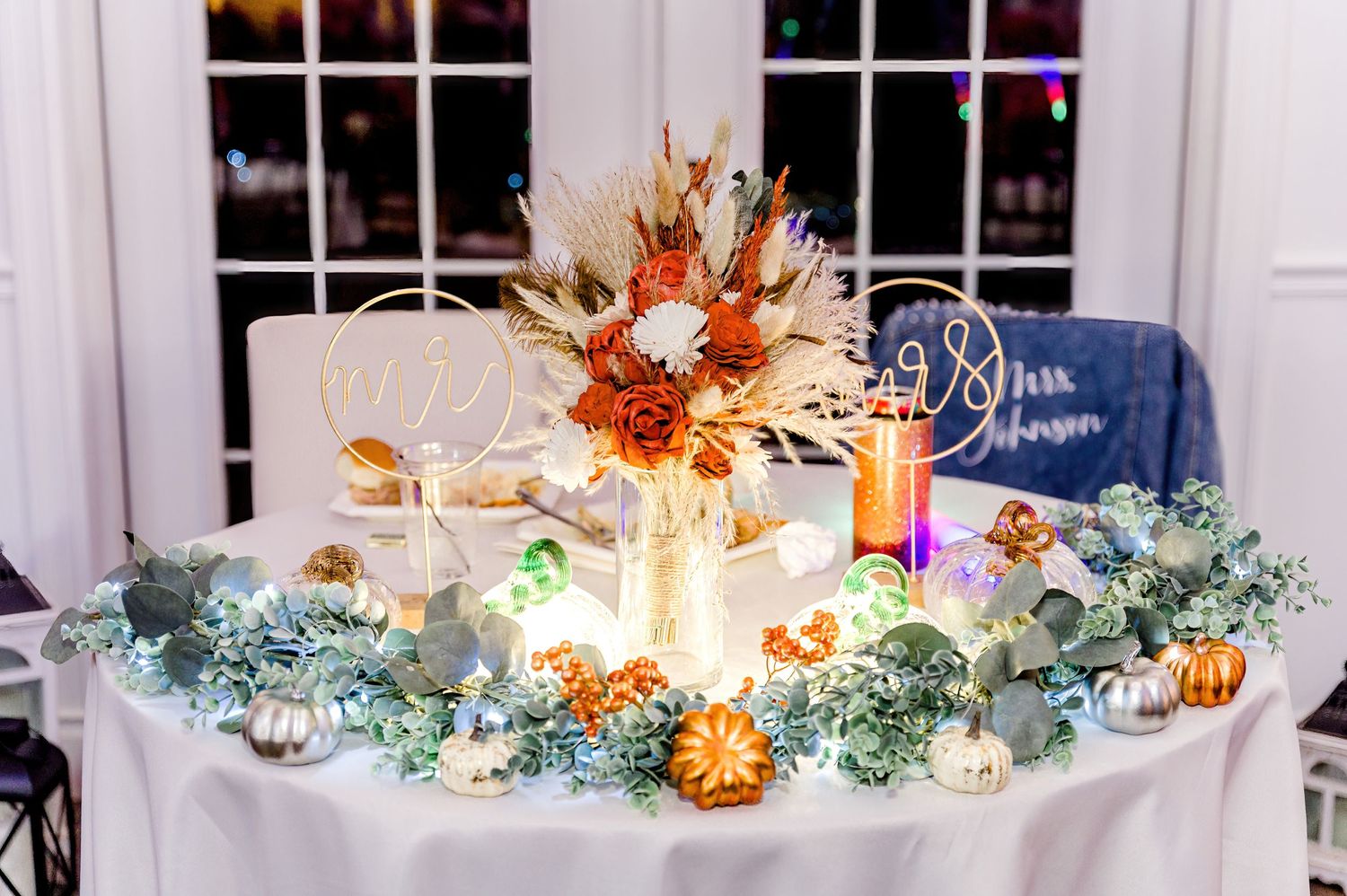Elegant fall wedding table centerpiece with glowing candles, dried flowers, and decorative greenery garland by Stephanie Coulter Photography