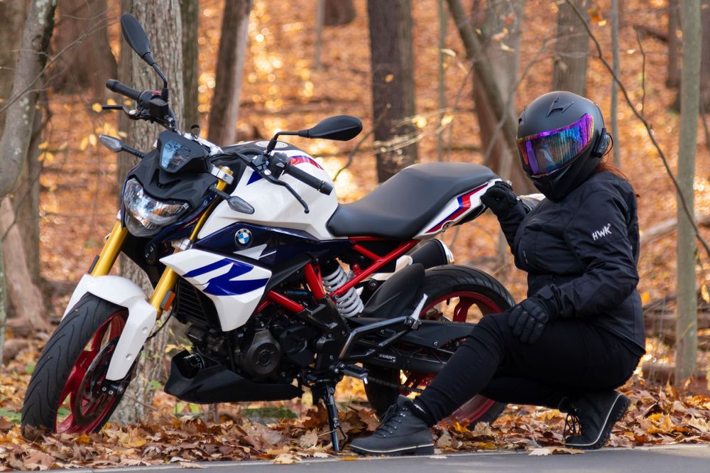 a woman bends down in front of a bmw motorcycle.