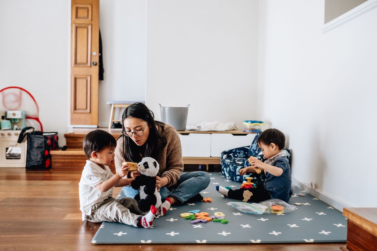 A mother playing with her twins on the playmat in their home in Perth