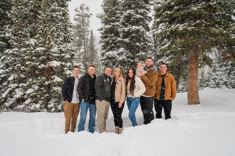 A group of friends pose together in a snow-covered forest setting.