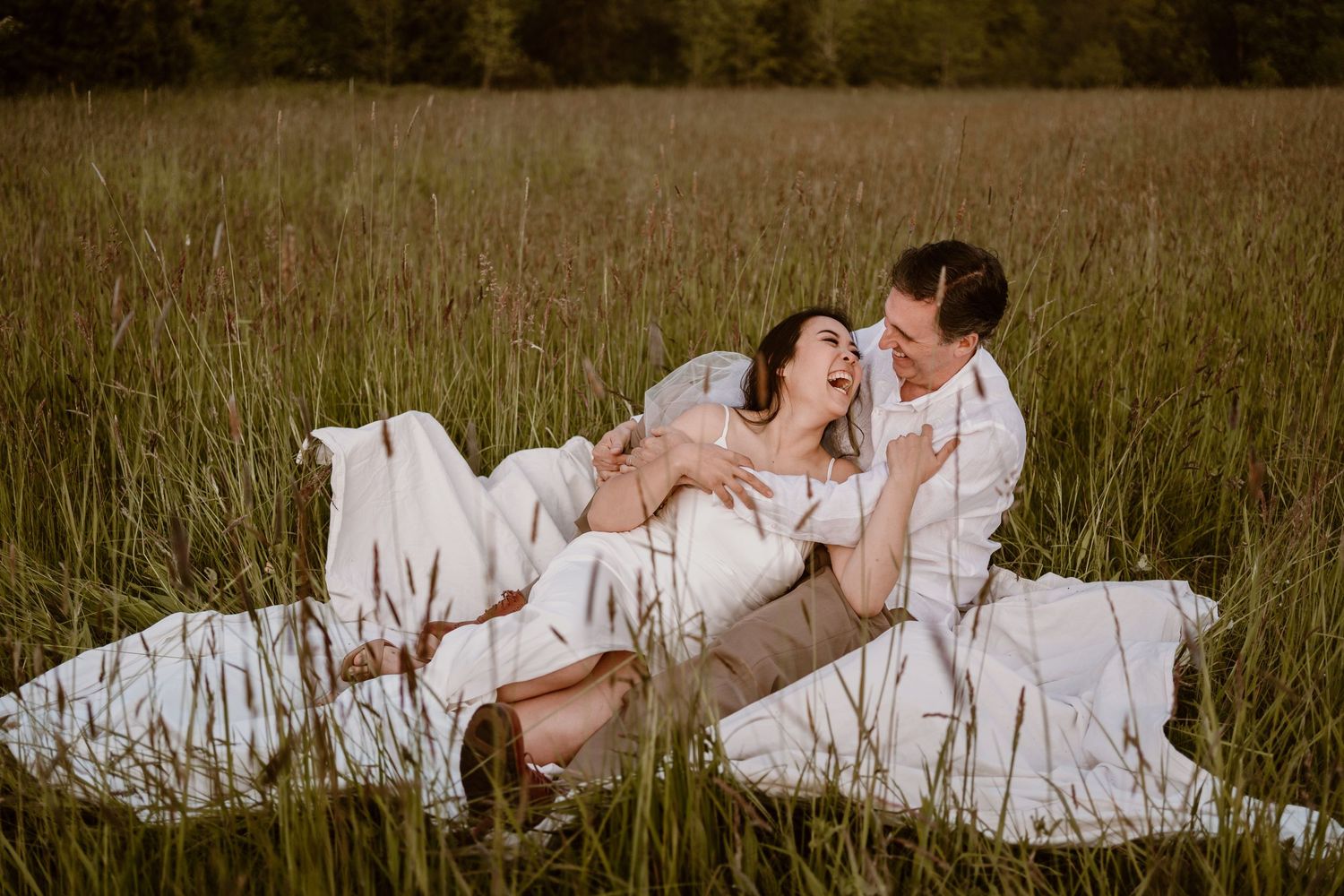 Intimate couple's portrait session in tall grass field during sunset.