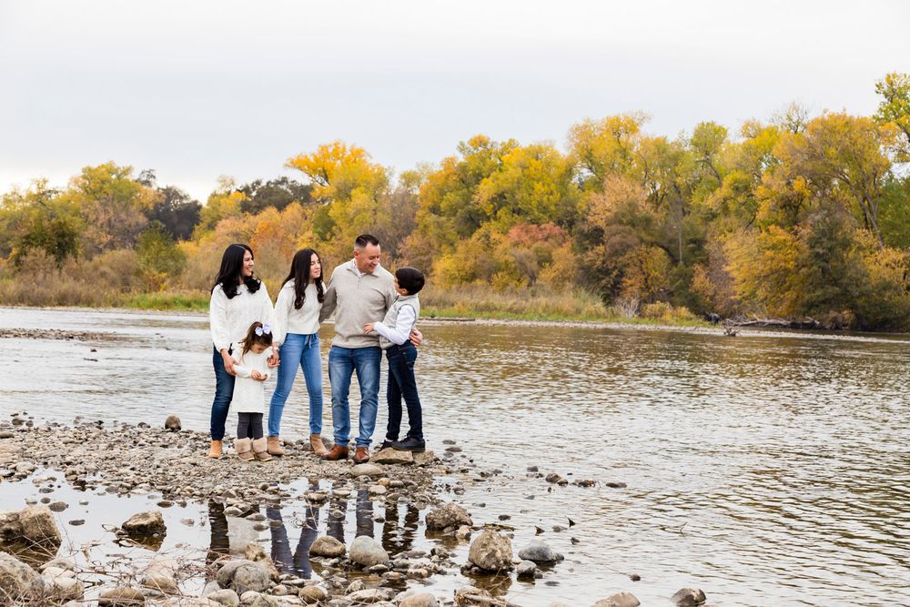 family on the bank of the American River in Sacramento in the fall with yellow and green leaves along the shore