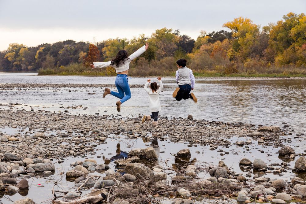 3 kids jumping on the shore of the American River in Sacramento