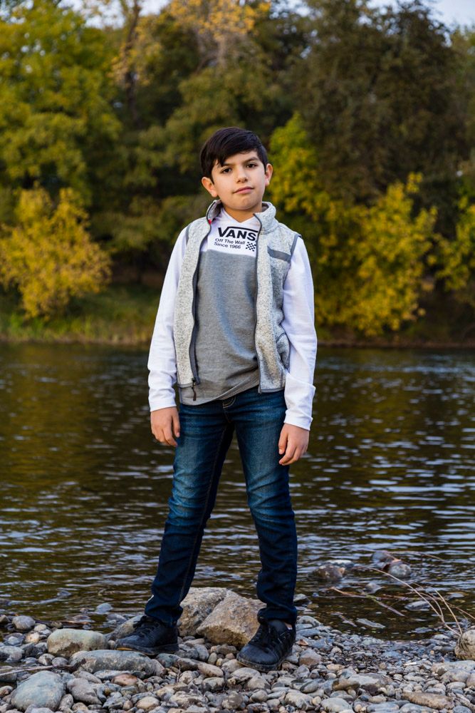 10 year old standing along the shore of a river
